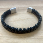 Black beaded bracelet with silver clasp on a wooden surface