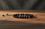 Black Obsidian and Hematite adjustable  bracelet on a wooden surface with a dark background