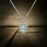 Moonstone Sphere Pendant Necklace on a wooden surface