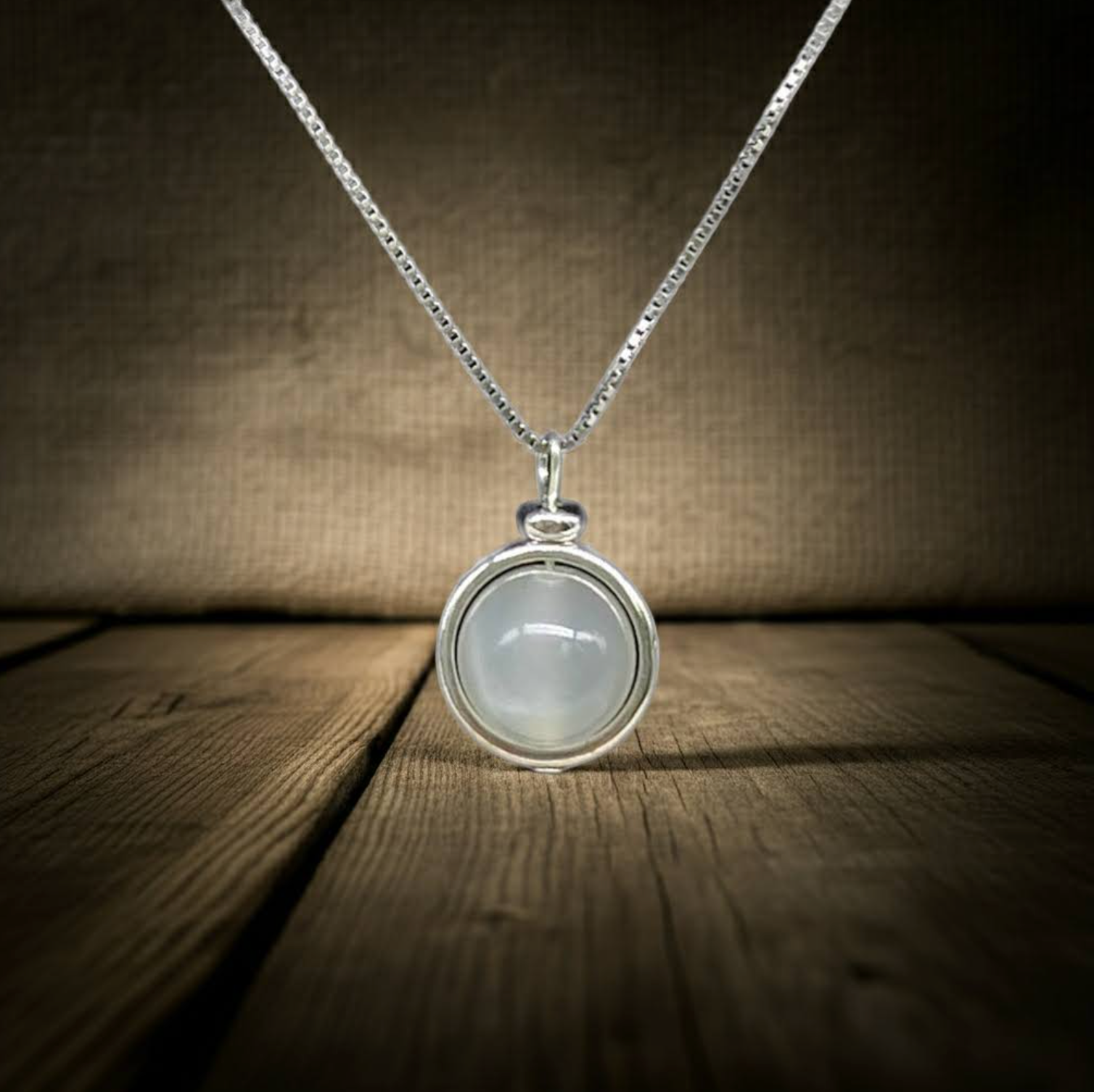 Moonstone Sphere Pendant Necklace on a wooden surface