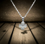 Silver four-leaf clover pendant necklace on a wooden surface